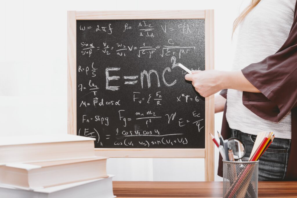 woman pointing to E=mc squared on small chalkboard