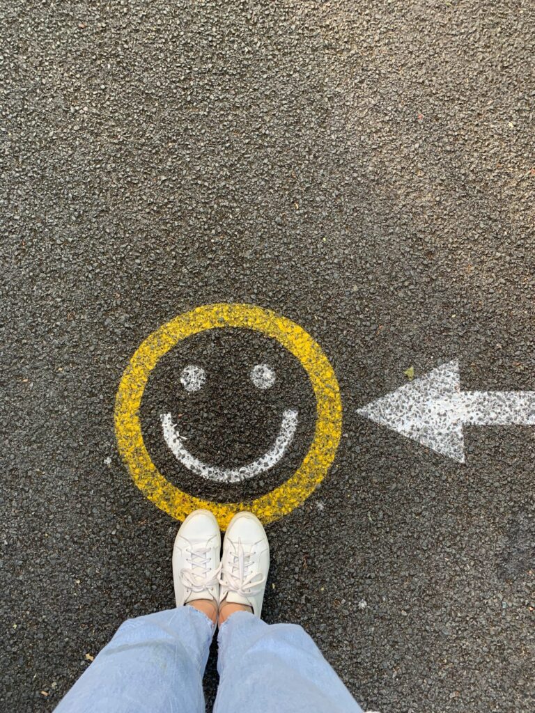 smiley face on pavement and white sneakers