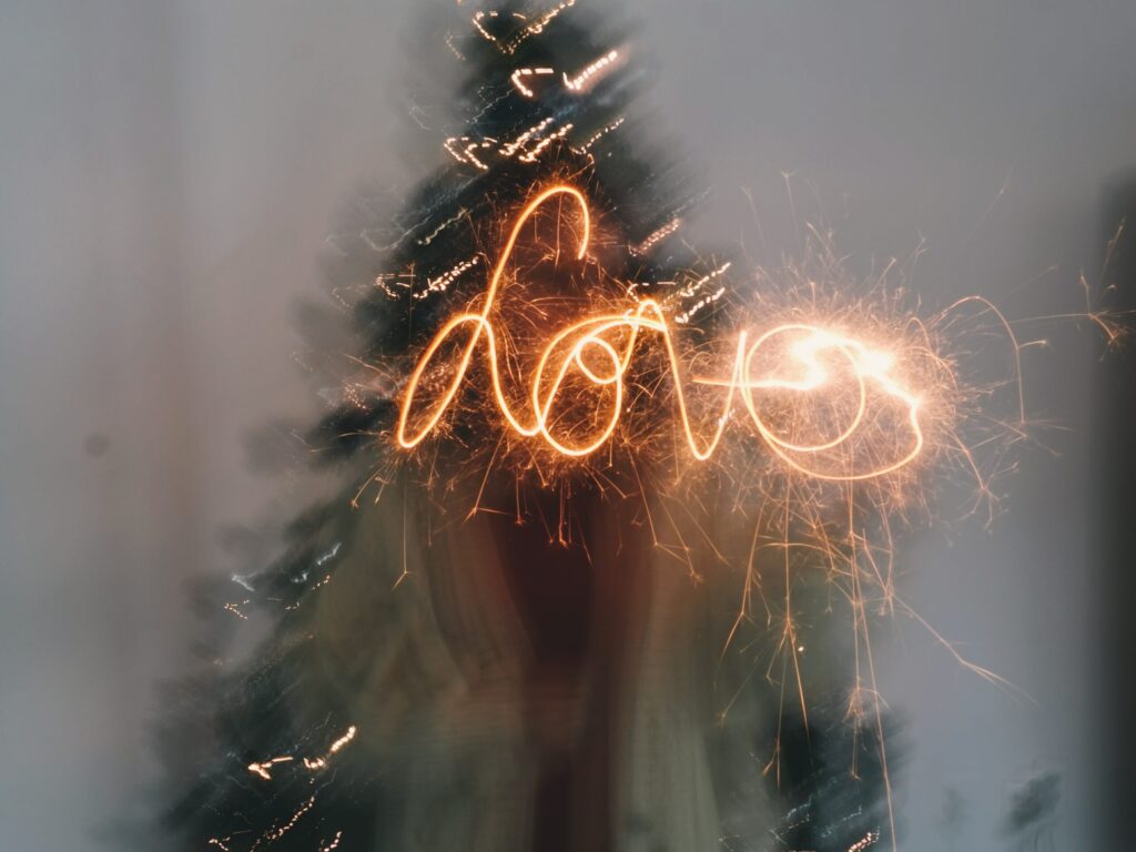 the word Love written over a blurred Christmas tree