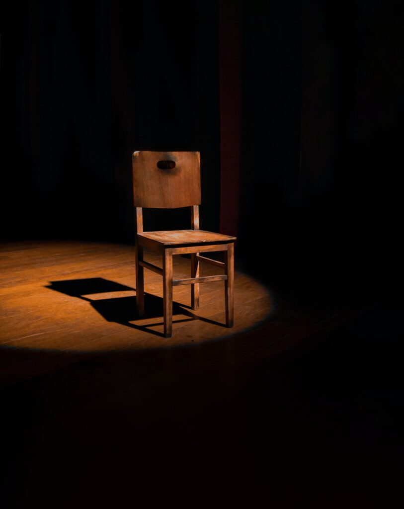 empty chair under spotlight on a stage